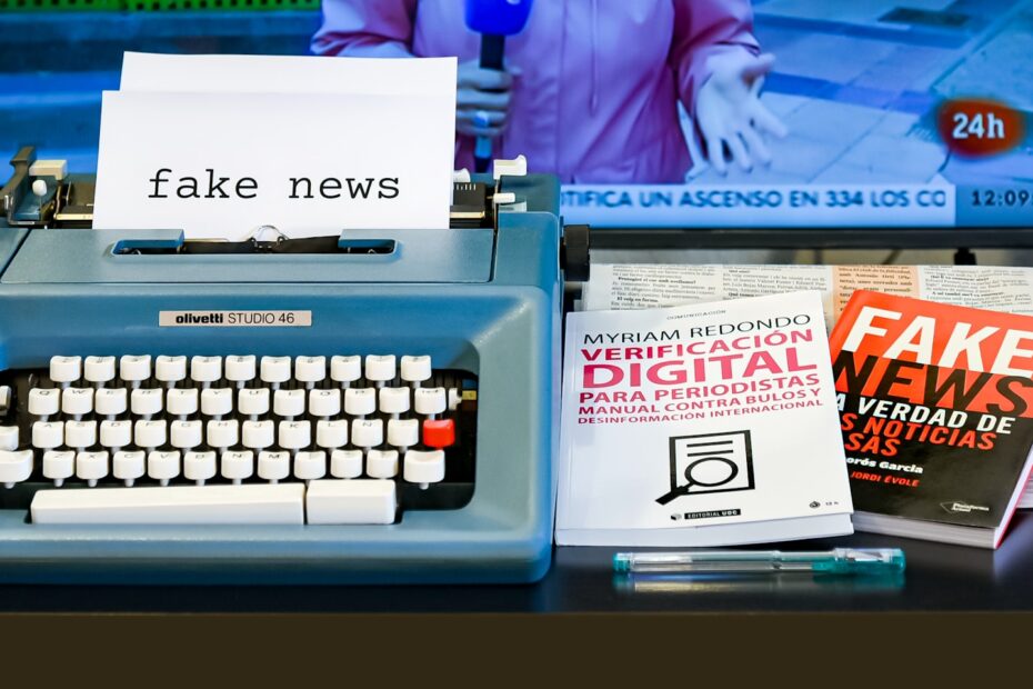 Typewriter with a paper that says fake news, with books on fake news beside it.